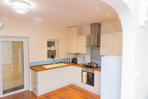 una cocina con armarios blancos y fregadero en Fortune 24 house, en Rainham