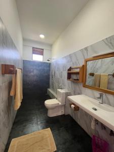 bagno con servizi igienici, lavandino e specchio di Swiss Residenz a Weligama