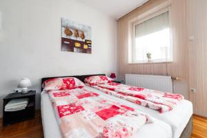 a bedroom with two beds with red and white blankets at Momo's studio apartment Subotica in Subotica
