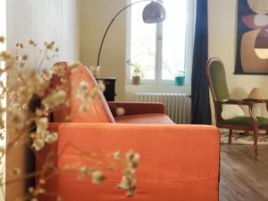 a living room with an orange couch and a chair at Studio avec sauna in Guéméné-sur-Scorff
