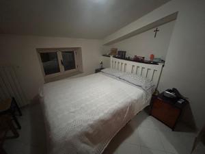 ein Schlafzimmer mit einem weißen Bett und einem Kreuz an der Wand in der Unterkunft Villa Castello in Montefalcione