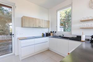 a white kitchen with white cabinets and a window at Villa de charme moderne avec piscine et vue mer in Nice