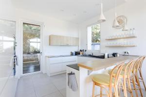 a kitchen with white cabinets and a counter with stools at Villa de charme moderne avec piscine et vue mer in Nice
