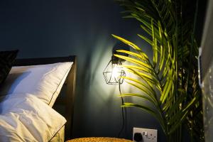 a lamp in a bedroom with a plant next to a bed at Boutique Docks Apartment - Parking in Gloucestershire