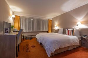 Un dormitorio con una cama blanca grande y un escritorio en Hotel Central, SPA & LOUNGE BAR, en Crans-Montana