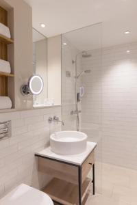 a white bathroom with a sink and a shower at Wyn. Strandhotel Sylt in Westerland (Sylt)