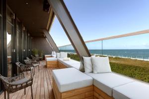 a balcony with white furniture and a view of the ocean at Wyn. Strandhotel Sylt in Westerland