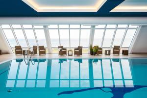 a swimming pool with chairs and a table in front of a large window at Wyn. Strandhotel Sylt in Westerland