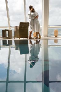 a woman standing in a room with a reflection in the water at Wyn. Strandhotel Sylt in Westerland (Sylt)