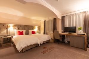 a hotel room with a bed and a desk and a television at Hotel Central, Spa & lounge bar in Crans-Montana