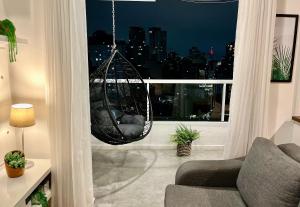 a hanging hammock in a living room with a window at Linda vista perto da Paulista com piscina/garagem in Sao Paulo