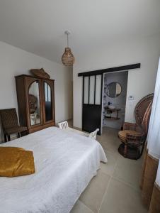 ein Schlafzimmer mit einem großen weißen Bett und einem Stuhl in der Unterkunft Le Clos des Gazanias in Grignols