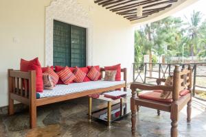 a couch with red pillows sitting on a porch at Villa Black Pearl - new private Villa in Diani Beach
