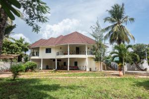 ein weißes Haus mit einem roten Dach und Palmen in der Unterkunft Villa Black Pearl - new private Villa in Diani Beach