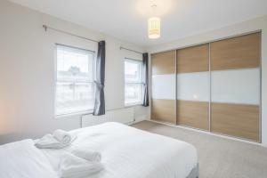 a bedroom with a large white bed and windows at Superb Central 2 Bed Home in Cherry Hinton