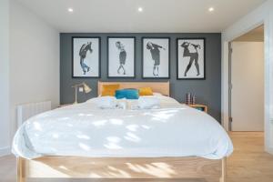 ein Schlafzimmer mit einem großen Bett mit vier Bildern an der Wand in der Unterkunft Luxury Central Riverside Apartment in Cambridge