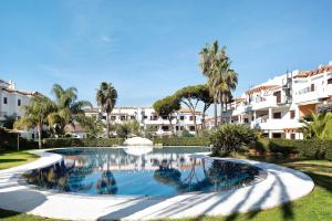 uma piscina num resort com palmeiras e edifícios em Atico Coto de Santi Petri 122 em Chiclana de la Frontera