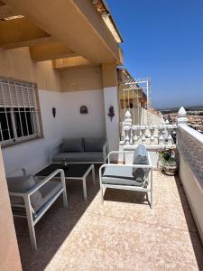 a patio with couches and tables on a balcony at Casa Gintare Torrevieja Beach in Torrevieja