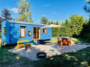 ein blaues winziges Haus mit einem Picknicktisch und einem Regenschirm in der Unterkunft Glamour Maringotka v NP České Švýcarsko U Mluvících kamenů in Staré Křečany