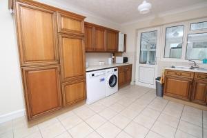 a kitchen with wooden cabinets and a washer and dryer at VERY SPACIOUS House For 6 In Fantastic Location in Cambridge