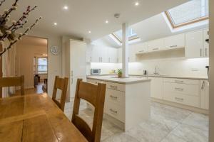 uma cozinha com armários brancos e uma mesa de madeira em LARGE 4 bedroom Home with Garden and Free Parking em Cherry Hinton