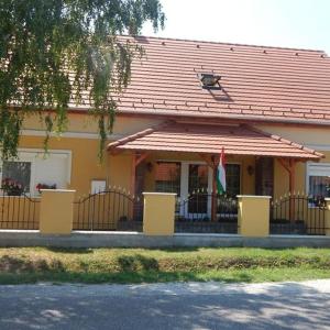 巴拉頓萊萊的住宿－Ferenc Vendégháza，黄色的房屋,有红色的屋顶和旗帜