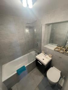 a bathroom with a toilet and a tub and a sink at Queens Park Vibrant 1BR Flat with Balcony in London