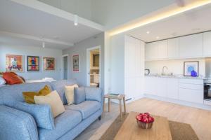 a living room with a blue couch and a kitchen at Luxury City Centre Apartment - Stunning Water View in Cambridge