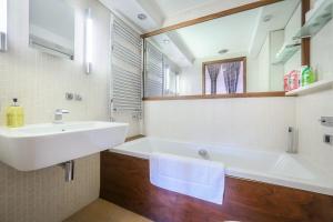 ein Badezimmer mit einem Waschbecken, einer Badewanne und einem Spiegel in der Unterkunft Large Luxurious CENTRAL Private Terrace - For 6 in London