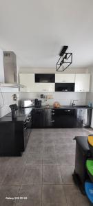 a large kitchen with black and white cabinets and a table at Villa individuelle 3 chambres - 6 pers in Calvi