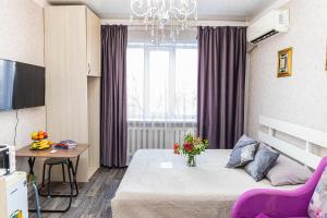 a small room with a bed and a table with flowers at YourHouse Микрорайон Жетысу-2, дом 66 in Almaty