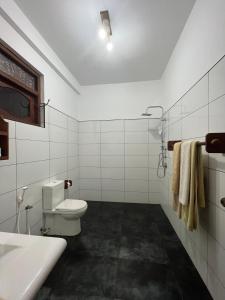 a white bathroom with a toilet and a sink at Swiss Residenz in Weligama