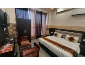 a hotel room with a bed and a desk and a television at Hotel Park Blu, panipat in Pānīpat