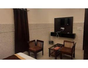 a bedroom with two chairs and a table and a tv at Hotel Park Blu, panipat in Pānīpat