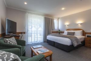 a hotel room with a bed and a couch and a tv at Amross Motel in Dunedin