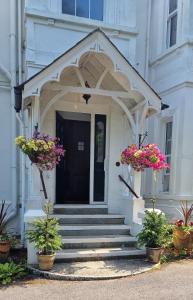 una porta d'ingresso di un edificio bianco con due piante in vaso di Claridge House a Lingfield