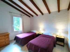 two beds in a room with purple sheets at Résidence Les Cigales in Porto-Vecchio