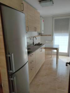 a kitchen with a stainless steel refrigerator and a table at Extraordinario ático de 80 m2 en urbaniz privada in Noja
