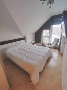 a bedroom with a large white bed and a chair at Extraordinario ático de 80 m2 en urbaniz privada in Noja