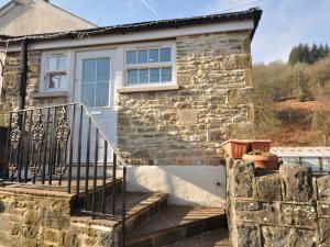 een stenen huis met een witte deur en een trap bij 1 Bed in Cinderford 73633 in Longney