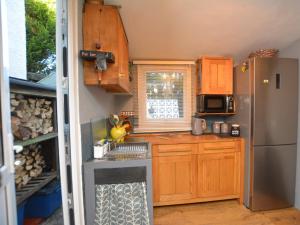 1 bed property in Trefor Beach 77891 في Llanaelhaiarn: مطبخ مع دواليب خشبية وثلاجة حديد قابلة للصدأ