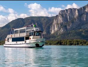 a boat on the water with mountains in the background at Tanjas gemütliches Haus am Mondsee in Innerschwand