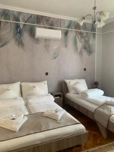 Cette chambre comprend 2 lits et un mur orné d'une fresque murale. dans l'établissement Szent István Apartman, à Makó