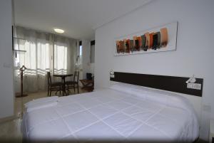 a bedroom with a large white bed and a table at Pintor Rosales 3 dormitorios mirando al mar - Fincas Arena in Benidorm +45 photos