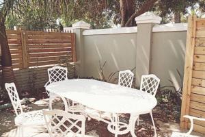 a white table and chairs next to a fence at Stylish family unit in Walmer in Gqeberha