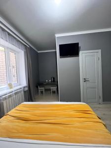 um quarto com uma cama com um cobertor amarelo em Мини-гостиница Береке em Aqtöbe