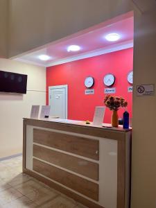 a counter with clocks on a red wall at Мини-гостиница Береке in Aktobe +20 photos