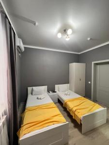 2 camas en una habitación con paredes amarillas y grises en Мини-гостиница Береке, en Aktobe