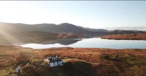 an aerial view of a house on a hill next to a lake at An Caladh in Balallan