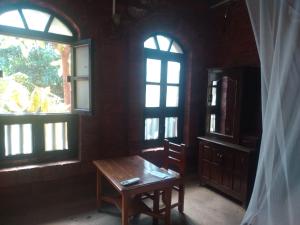 um quarto com uma mesa de madeira e 2 janelas em Konkan Nest Resort em Ganpatipule